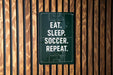 a sign with the text "EAT. SLEEP. SOCCER. REPEAT."