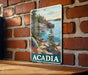 A metal sign with a scenic image of a coastal landscape in Acadia National Park, Maine, hanging on a brick wall.