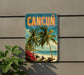 A vintage-style sign with the word "CANCUN" prominently displayed, featuring palm trees, a beach, and a clear blue sky.