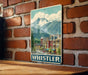 A vintage-style metal sign depicting a mountain town with colorful buildings and a clear blue sky.