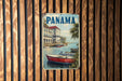 A vintage metal sign with the word "PANAMA" prominently displayed, featuring a scenic image of boats on a body of water.