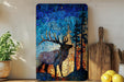 a vibrant mosaic artwork depicting a deer with large antlers, set against a backdrop of a forest. The artwork is displayed on a wooden shelf, with a potted plant and a wooden cutting board nearby.