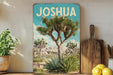 A vintage-style metal sign with a desert landscape featuring a Joshua tree, placed on a wooden shelf next to a cutting board and some potted plants.