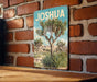 A vintage-style metal sign with a desert landscape and a palm tree, mounted on a brick wall.
