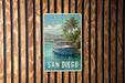 A vintage-style sign for San Diego, featuring a boat on a tropical beach with palm trees and a blue sky.
