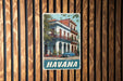 A vintage-style metal sign with a photograph of a building and a car, mounted on a wooden wall.