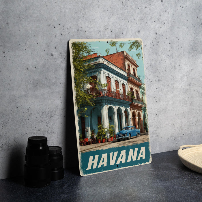 A vintage metal sign featuring an image of a colorful building in Havana, Cuba, with a classic car parked in front.