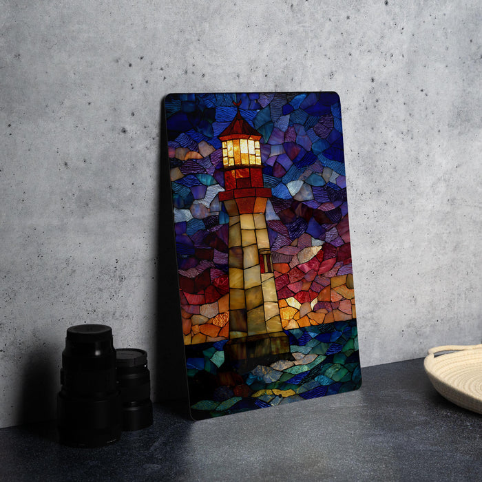 A vibrant stained glass artwork depicting a lighthouse is displayed on a gray wall, accompanied by a stack of black camera lenses and a woven basket.