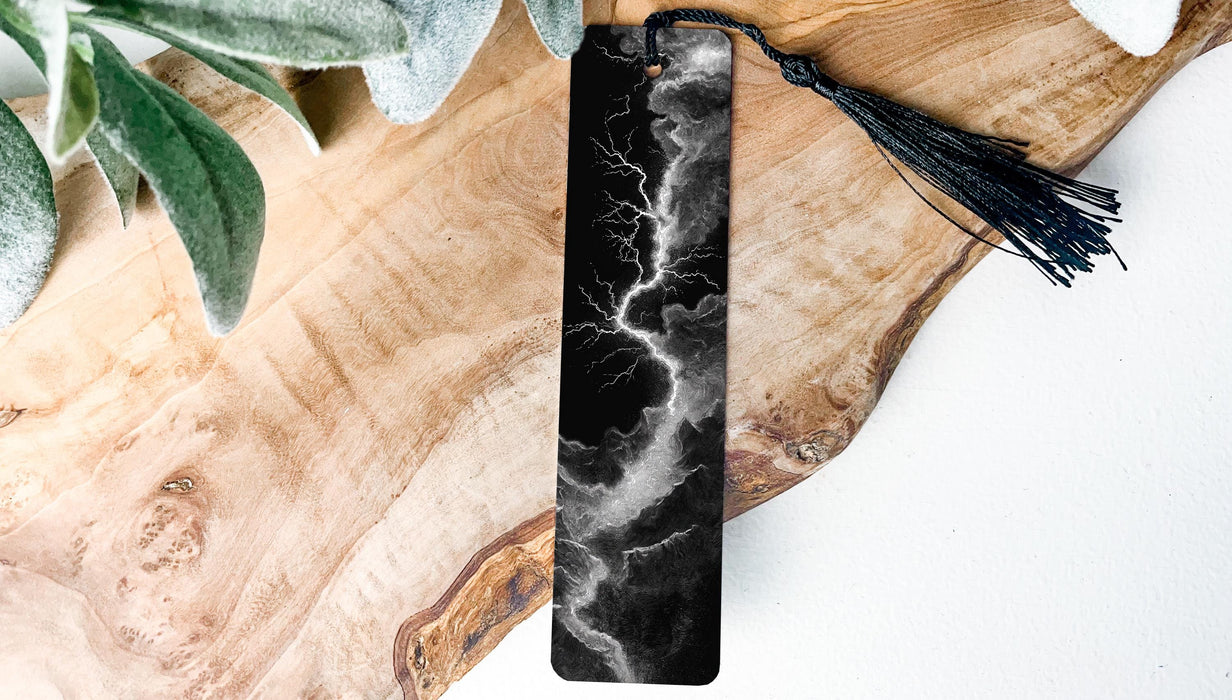 A black and white bookmark with a tassel attached, resting on a wooden surface.