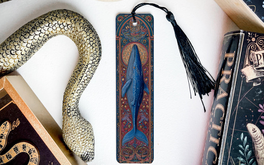 a blue whale bookmark with a black tassel, placed between two books.