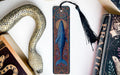 a blue whale bookmark with a black tassel, placed between two books.