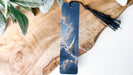A wooden surface with a blue bookmark featuring a picture of a sailboat on the water.