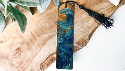 A wooden bookmark with a wave design and a black tassel is displayed on a wooden surface.