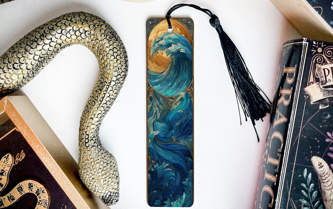 a decorative snake-shaped bookmark with a wave design on it, placed next to a book and a tassel.