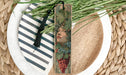 a decorative bookmark with a floral design, placed on a plate with a striped pattern.