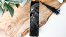 A close-up of a bird's face, possibly a hawk or falcon, is featured prominently on a wooden surface, with a black tassel hanging from the top.