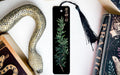 a black bookmark with a decorative snake design on it, placed next to a book and a decorative snake toy.