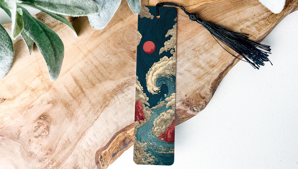A vertical wooden bookmark with a tassel attached, featuring an illustration of a wave and a red sun in the sky.