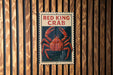 A sign with the text "RED KING CRAB" and an illustration of a red crab is displayed on a wooden wall.