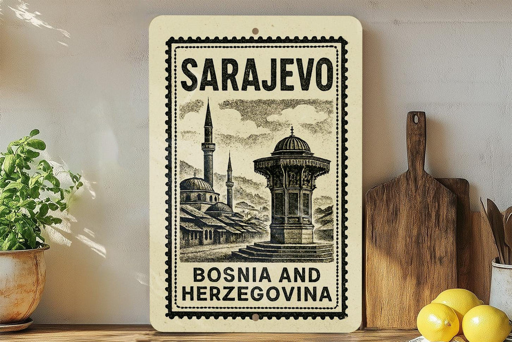 a vintage-style stamp or sign with the text "SARajevo Bosnia and Herzegovina" on it, placed on a shelf next to a potted plant and a wooden cutting board.