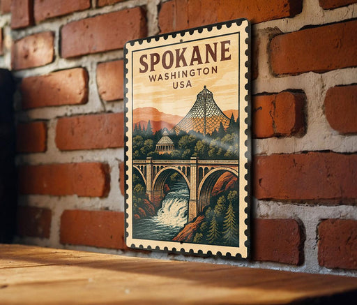 A wooden sign with a vintage-style illustration of a bridge and waterfall, mounted on a brick wall.