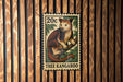 A 20c postage stamp featuring a kangaroo, mounted on a wooden wall.