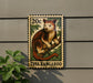 A tree kangaroo stamp is displayed on a wall, with a plant in the foreground.