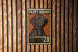 A U.S. postage stamp featuring a hound dog, mounted on a wooden wall.