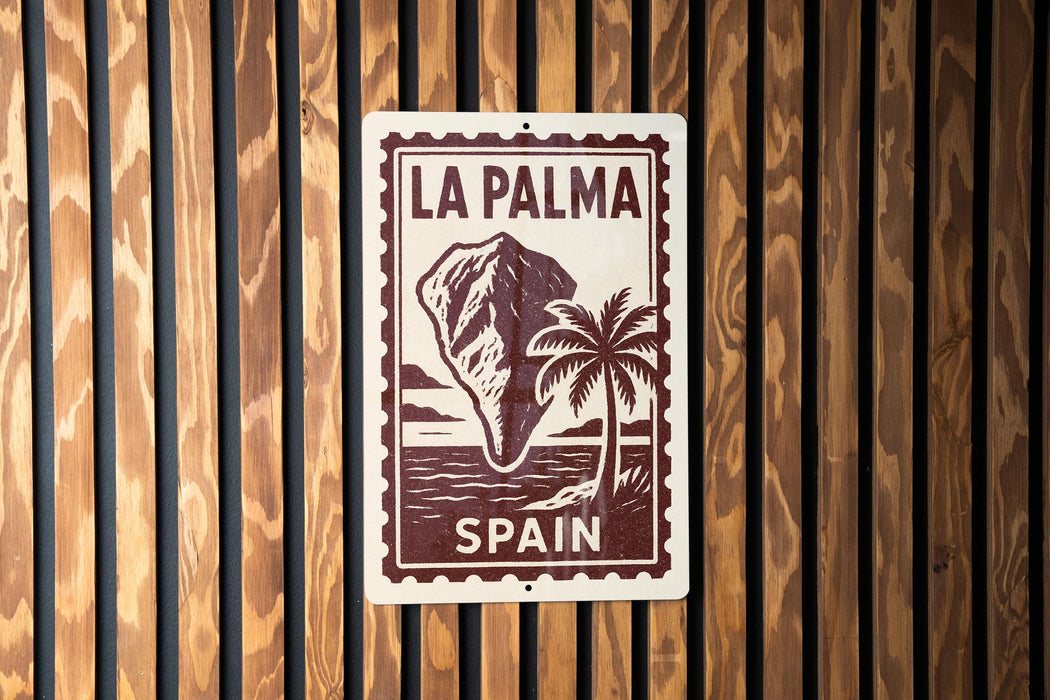 A sign with the text "LA PALMA" and "SPAIN" printed on it, along with a palm tree and a mountain, is displayed on a wooden wall.