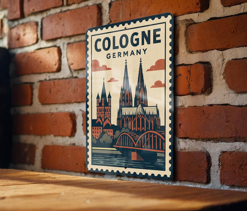 A vintage-style metal sign with a graphic of the Cologne Cathedral in Germany, mounted on a brick wall.