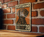 A vintage-style metal sign featuring a dog illustration and the text "PLOTT HOUND" and "U.S. POSTAGE 20" is displayed on a brick wall.