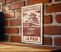 A vintage-style metal sign with a castle illustration and the text "Himeji Castle Japan" is displayed on a brick wall.