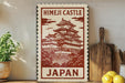 A vintage-style sign depicting the Himeji Castle in Japan, with a wooden board and a potted plant in the foreground.