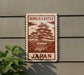 A sign displaying the name of a castle, "Himeji Castle", with a picture of the castle on it. The sign is mounted on a wall, and there is a plant to the left of the sign.