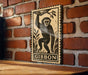 a wooden table with a framed illustration of a monkey hanging from a branch on the wall behind it.