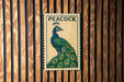 A metal sign featuring a colorful illustration of a peacock is mounted on a wooden wall.