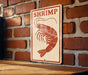 A sign with the word "SHRIMP" on it is displayed on a brick wall.