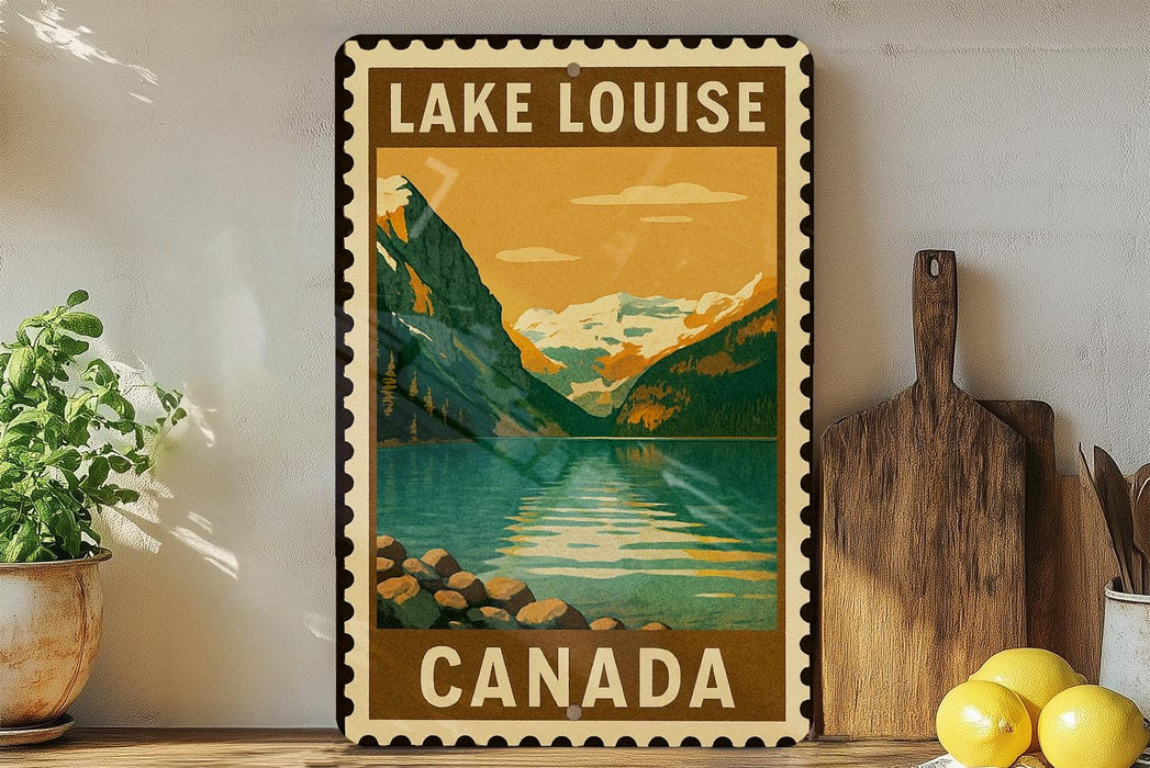 A vintage-style metal sign with the text "LAKELOUISE CANADA" displayed prominently, featuring a scenic mountain landscape with a lake and mountains in the background.