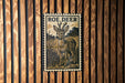 A metal plaque featuring an illustration of a roe deer standing in a grassy field.