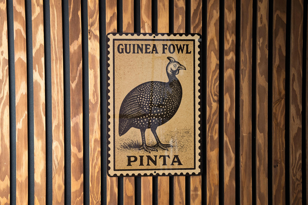 A metal sign with a bird illustration and text, mounted on a wooden wall.