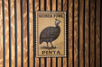 A metal sign with a bird illustration and text, mounted on a wooden wall.