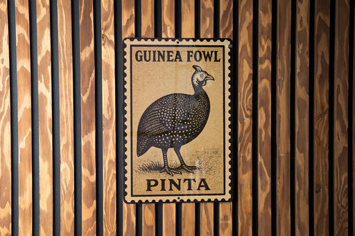 A metal sign with a bird illustration and text, mounted on a wooden wall.