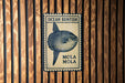 a blue and white sign with a picture of a fish, mounted on a wooden wall.