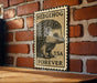 A vintage-style metal stamp featuring a hedgehog is displayed on a brick wall.