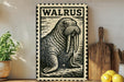 A walrus illustration on a framed piece of art is displayed on a shelf, accompanied by a wooden cutting board, a potted plant, and some lemons.