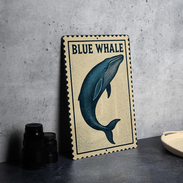 a metal sign with a blue whale illustration, placed on a countertop next to some black camera lenses.