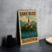A metal sign with the text "LAKE BLEED SLOVENIA" and an illustration of a church on a lake, set against a mountainous landscape.