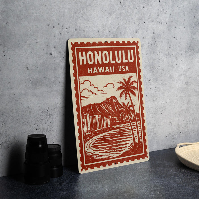 A red and white sign with the text "HONOLULU HAWAII USA" and an illustration of a beach and mountain landscape.