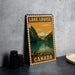 A vintage-style metal sign with the text "LAKELOUSE CANADA" and an illustration of a mountain landscape with a lake.