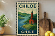 A vintage-style metal sign with a landscape depicting a church and a river, mounted on a wall next to a wooden cutting board and a potted plant.